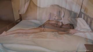 Una gimnasta flexible desnuda en la cama